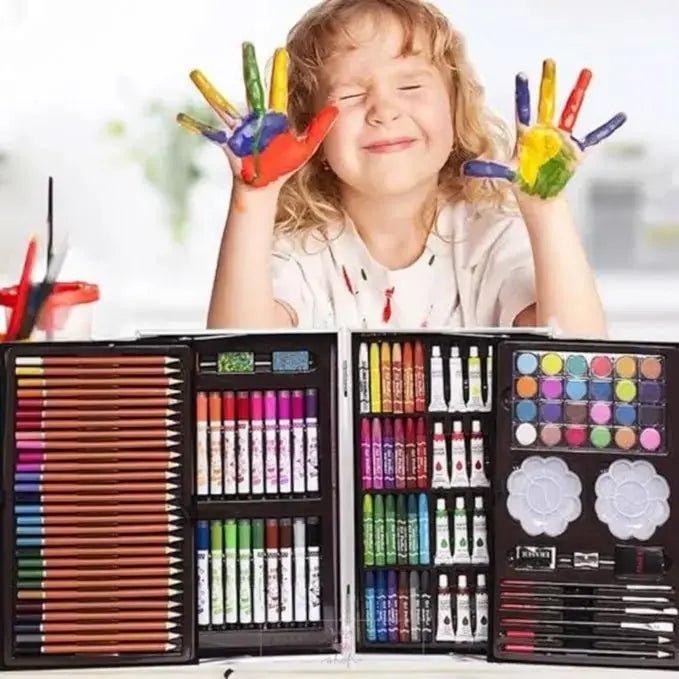 Happy child with painted hands using a kids art kit featuring crayons, color pencils, oil pastels, watercolors, and paintbrushes in an organized case.