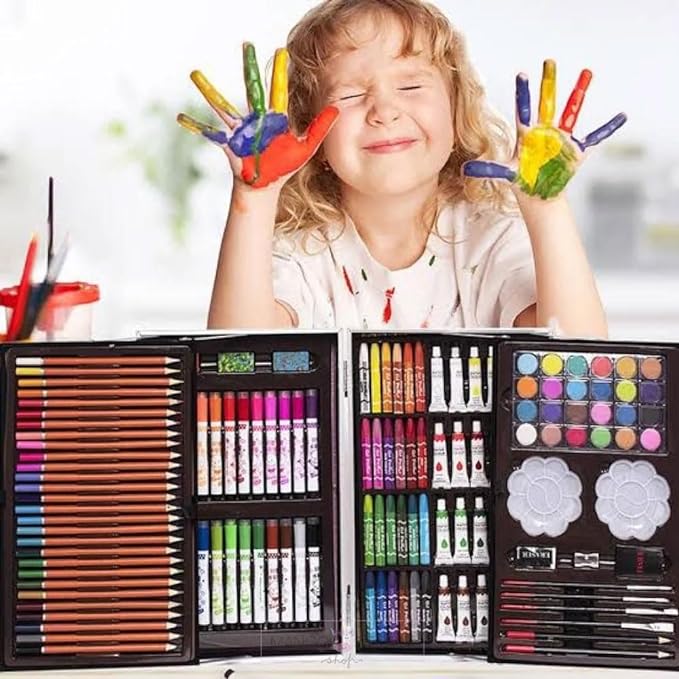 Happy child with painted hands using a kids art kit featuring crayons, color pencils, oil pastels, watercolors, and paintbrushes in an organized case.
