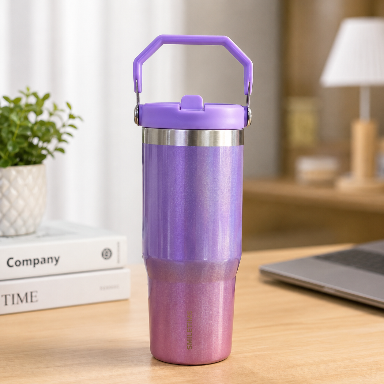Purple insulated tumbler on a desk with books and a laptop in the background