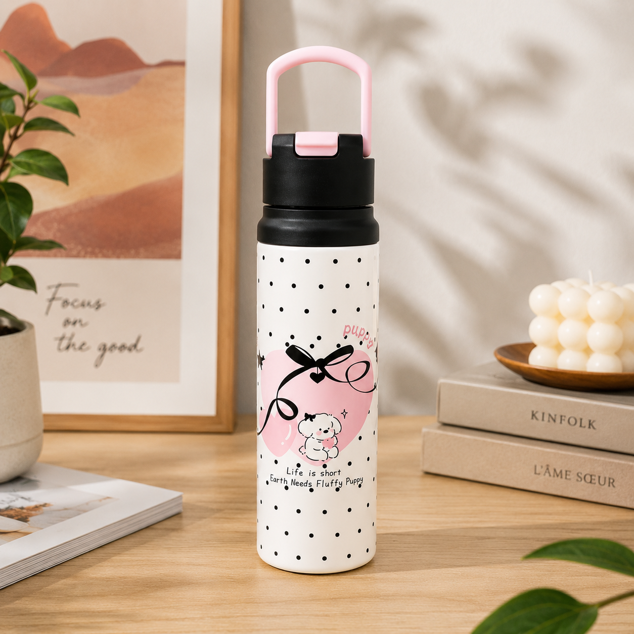 White water bottle with black polka dots and pink accents on a wooden surface.
