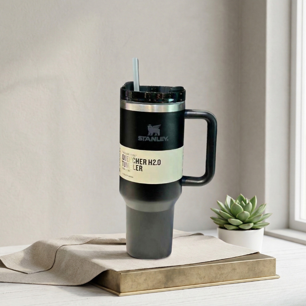 Stanley travel mug on a surface with a plant in the background