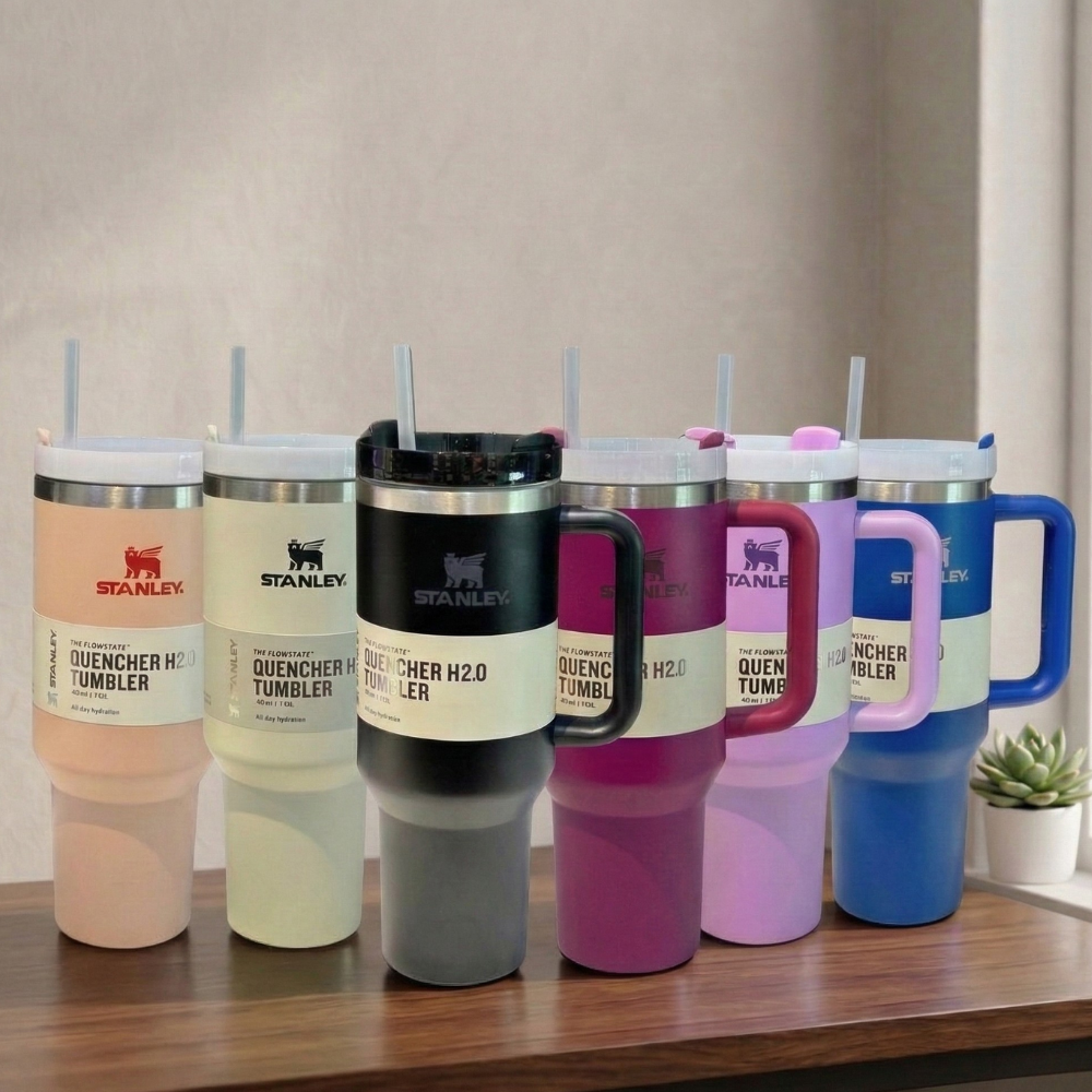 Set of Stanley tumblers in various colors on a wooden surface with a neutral background.