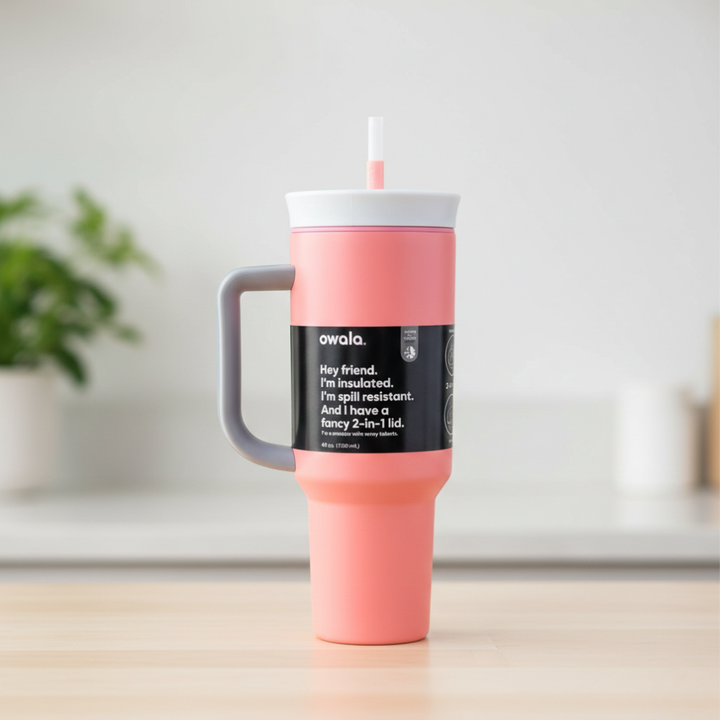 Pink tumbler with a black label on a wooden surface