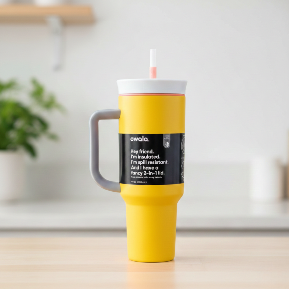 Yellow tumbler with a gray handle on a wooden surface, featuring the Owala brand.