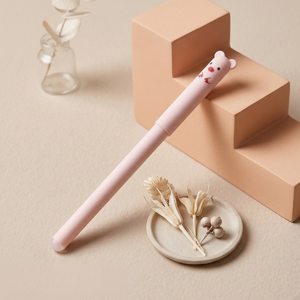 Pink pen with a bear-shaped cap on a beige surface with decorative elements