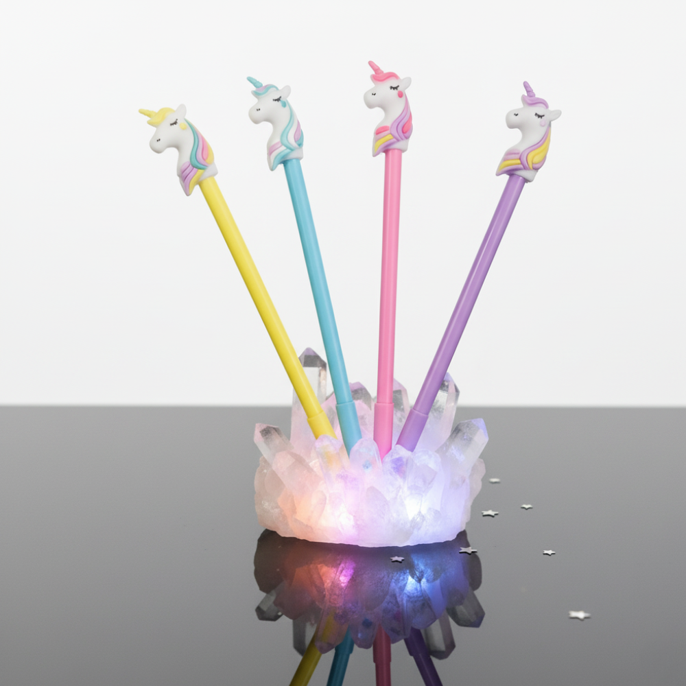 Four colorful pens with unicorn tips in a holder on a reflective surface.