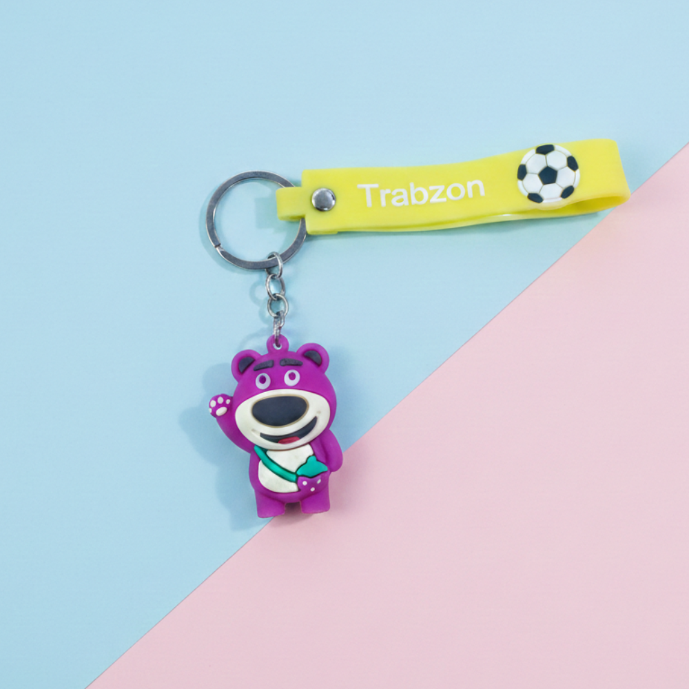 Keychain with a purple bear charm and yellow strap labeled 'Trabzon' on a pink and blue background