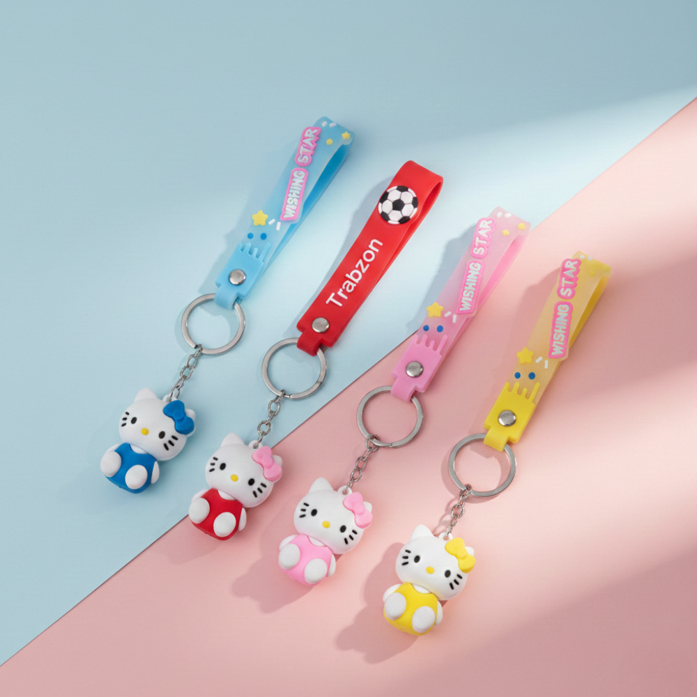 Four colorful keychains with cartoon characters on a pink and blue gradient background