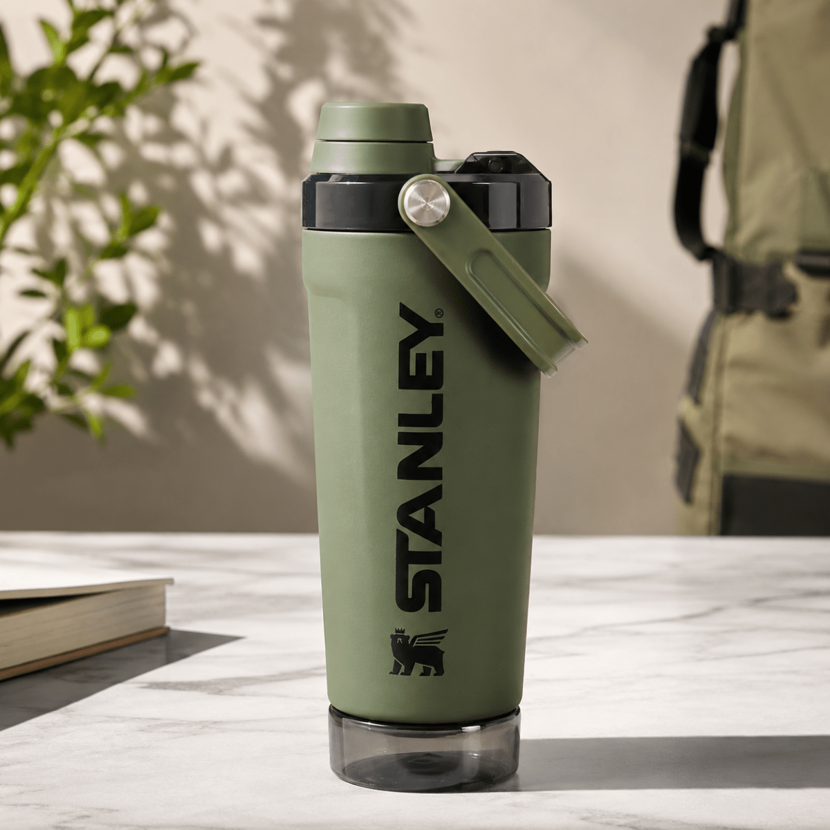 Activate Shaker BottleInsulated Water BottleCrafty CuddleStanley water bottle in olive green with a black logo and a matching green carrying loop, sitting on a light marble surface with a blurred background.Olive GreenShakerBottle ProteinShaker GymBottle FitnessEssentials WaterBottle WorkoutGear LeakproofBottle BPAFree SportsBottle Hydration