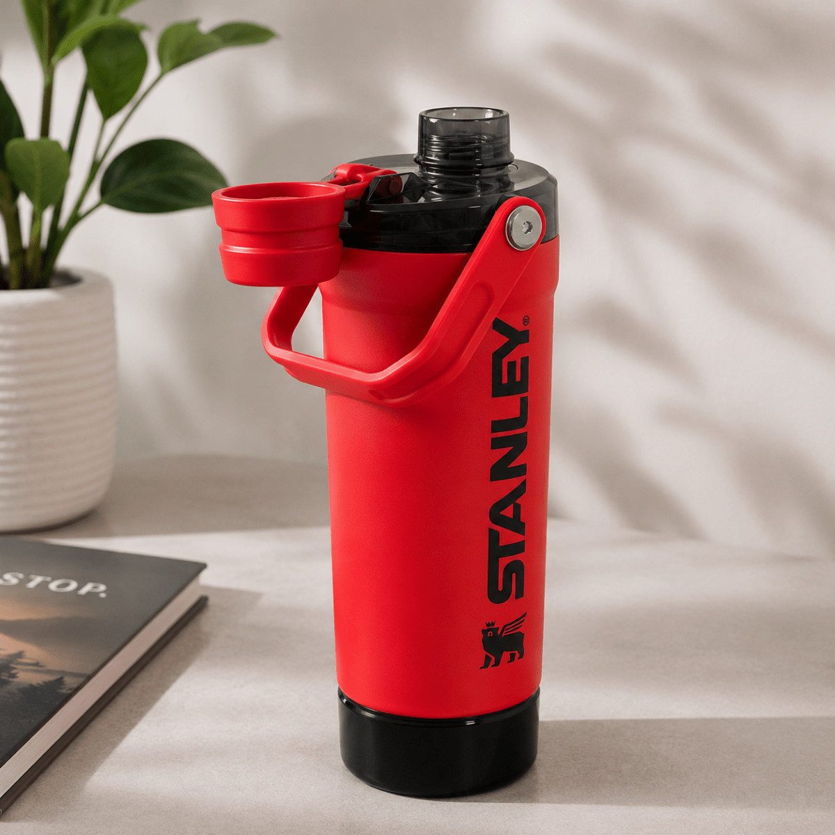 Activate Shaker BottleInsulated Water BottleCrafty CuddleA red Stanley insulated water bottle with a black base and a flip-up lid, shown on a tabletop with a plant and book in the background.RedShakerBottle ProteinShaker GymBottle FitnessEssentials WaterBottle WorkoutGear LeakproofBottle BPAFree SportsBottle Hydration