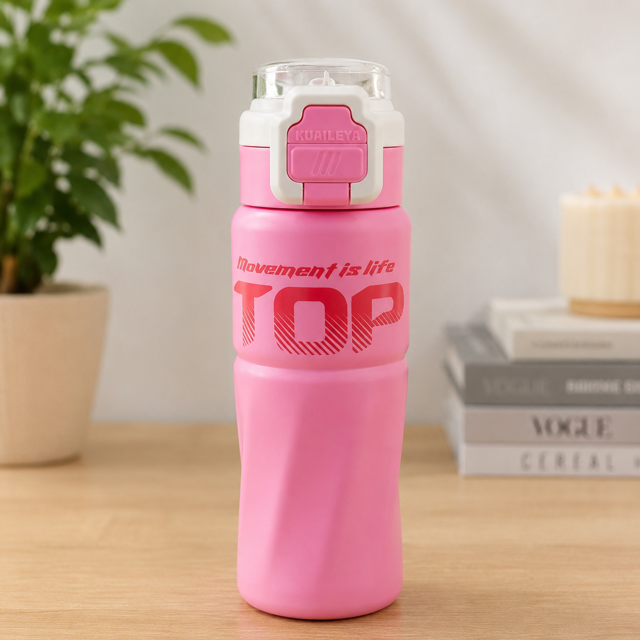 Pink water bottle with white cap on a wooden surface, plant and books in the background