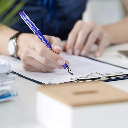 Person writing on a document with a blue pen, blurred background