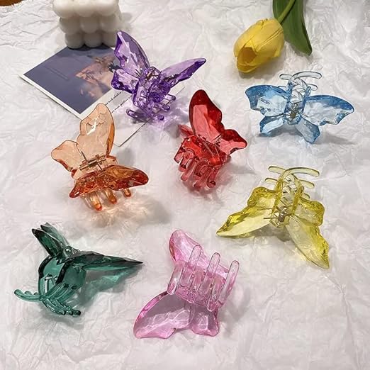 Colorful butterfly-shaped hair clips on a textured surface with tulips in the background.