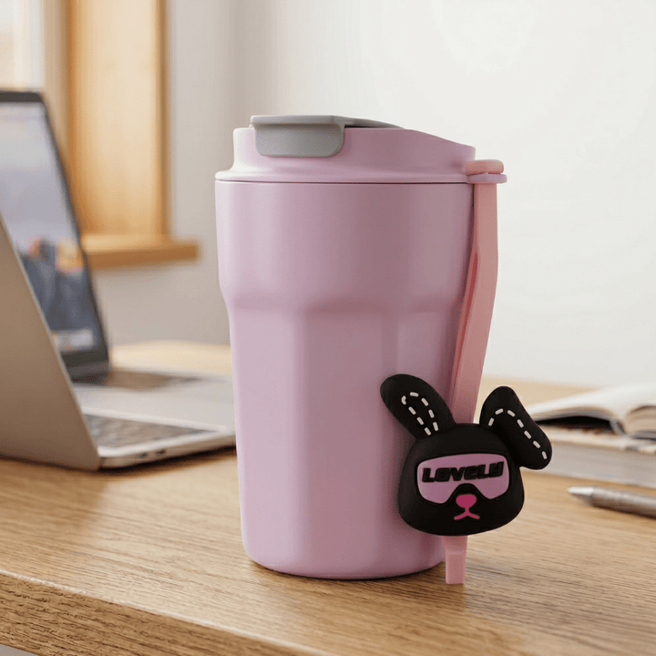 Cartoon Charm Insulated Coffee TumblerInsulated Coffee TumblerCrafty CuddlePink travel mug with a cartoon dog tag on a desk next to a laptopPinkCuteTumbler AestheticCups TrendyDrinkware PastelVibes KawaiiStyle ReusableCup HydrationGoals CuteAccessories GiftIdeas HomeEssentials