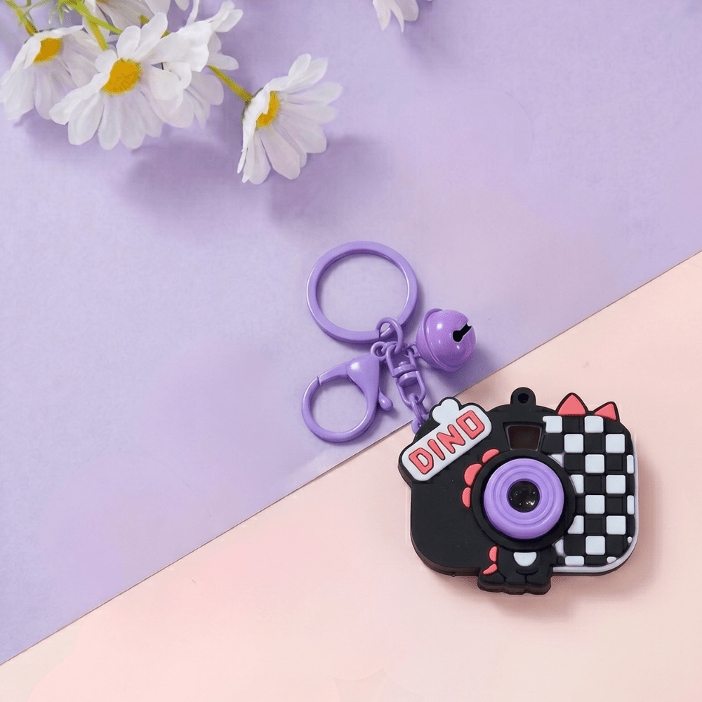 Cute Camera Shape Projector KeychainKeychainsCrafty CuddleDinosaur - themed camera keychain with a bell on a pastel background with flowersBlackCuteKeychain KawaiiAccessories KidsAccessories ReturnGiftIdeas CartoonKeychain MiniCamera BagCharm StationeryLove GiftForKids TrendingNow