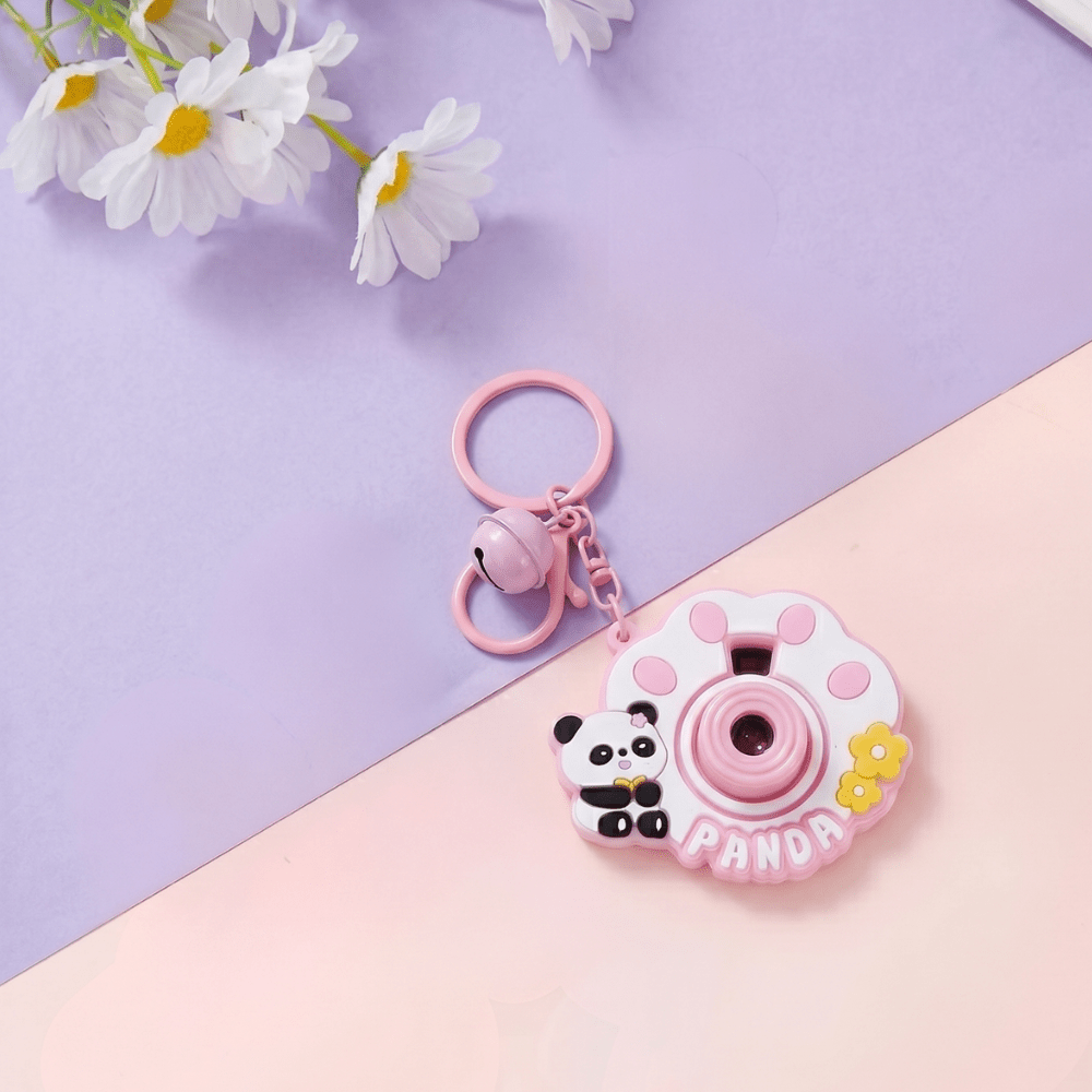 Cute Camera Shape Projector KeychainKeychainsCrafty CuddlePink panda - themed camera - shaped keychain on a two - tone purple and pink background with white flowers.PinkCuteKeychain KawaiiAccessories KidsAccessories ReturnGiftIdeas CartoonKeychain MiniCamera BagCharm StationeryLove GiftForKids TrendingNow