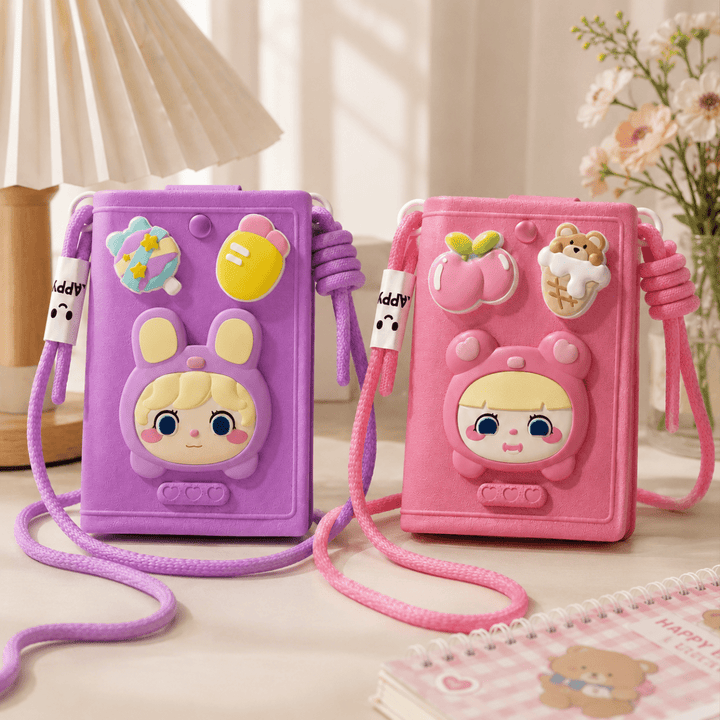 Cute Cartoon Crossbody Phone Bag for GirlsKids BagsCrafty CuddleTwo cute mini crossbody phone bags, one purple and one pink, displayed side-by-side on a light-colored tabletop. The bags feature a 3D cartoon character face on the front, decorative fruit and candy charms, and thick braided straps.PinkCuteCrossbodyBag PhoneBag MiniSlingBag KawaiiStyle GirlsFashion CrossbodyBag CuteAccessories FashionAccessories MobilePouch ShopifyFindsStationeryAddict