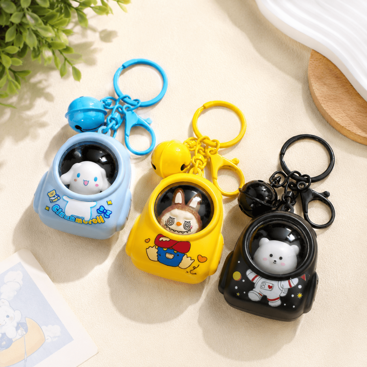 Cute Cartoon LED Keychain with BellKeychainsCrafty CuddleThree cute cartoon keychains shaped like small capsule vehicles, shown on a light beige surface with decorative props. One is light blue with a white character and blue bell, one is yellow with a rabbit character and yellow bell, and one is black with an astronaut character and black bell.CuteKeychain CartoonKeychain BagCharm KeychainCollection KawaiiAccessories CuteAccessories GiftIdeas ReturnGifts StationeryLovers CraftyCuddleStationeryA