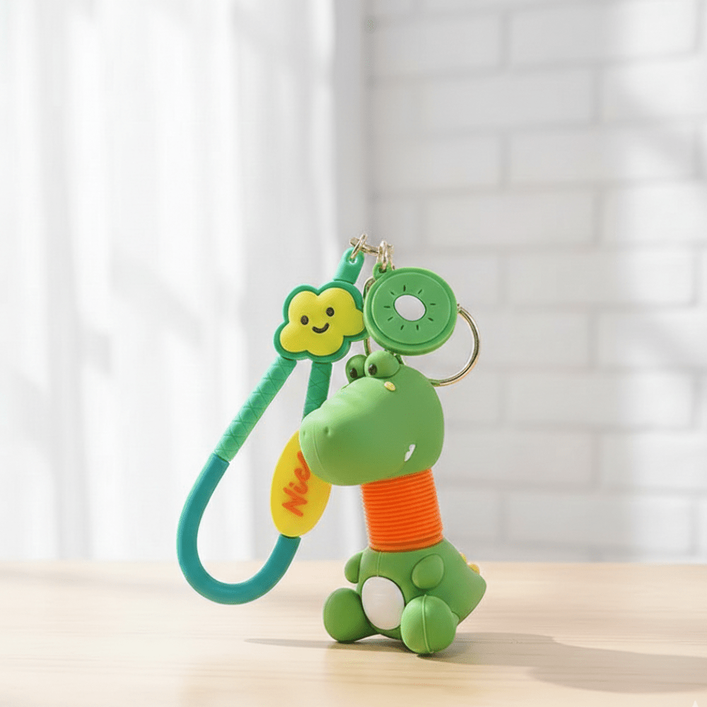 Cute Cartoon Stretchy KeychainKeychainsCRAFTY CUDDLEGreen dinosaur - shaped keychain with a spring on a light wooden surface and white curtain backgroundDinosaurCuteKeychain KawaiiAccessories KidsStationery ReturnGiftIdeas PartyFavor BackpackCharm FidgetToy KidsGifts TrendingToys BagAccessories