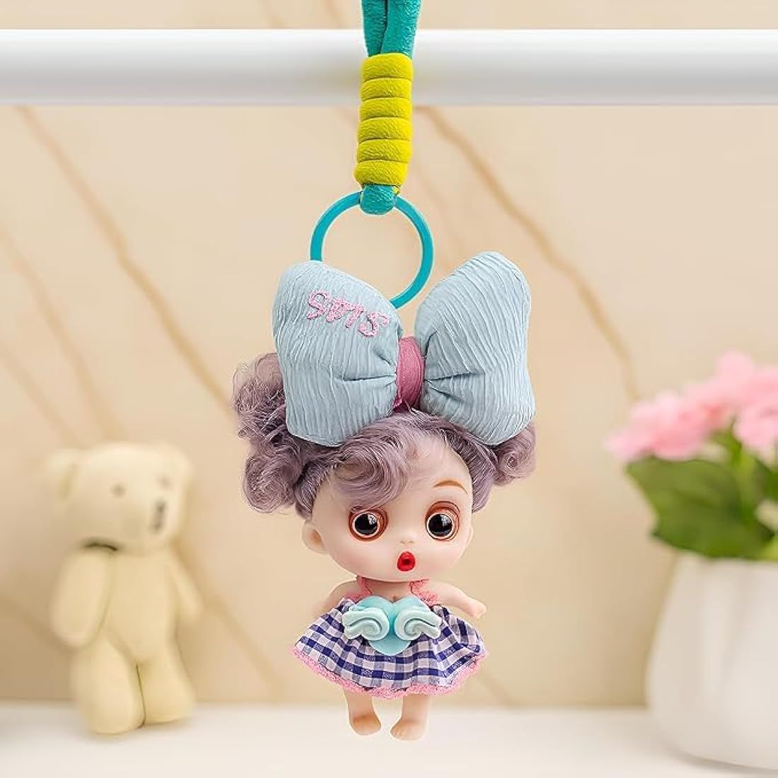 Cute Mini Doll Keychain for GirlsKeychainsCRAFTY CUDDLEDoll keychain with large bow and checkered dress hanging from a bar with a soft backgroundBlue Bow DollDollKeychain CuteAccessories GirlsAccessories BagCharm ReturnGiftIdeas KidsFashion KawaiiStyle PrincessTheme BirthdayReturnGift MiniDoll