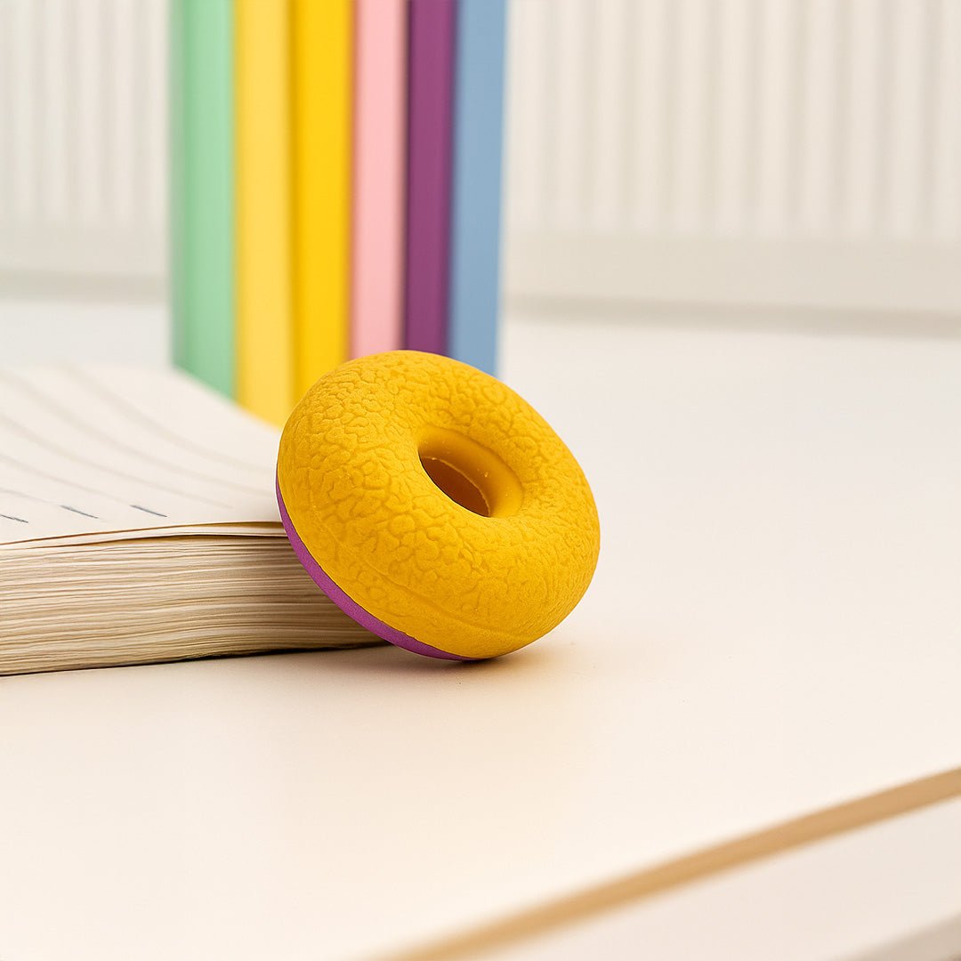 Yellow donut-shaped object on a white surface with books in the background