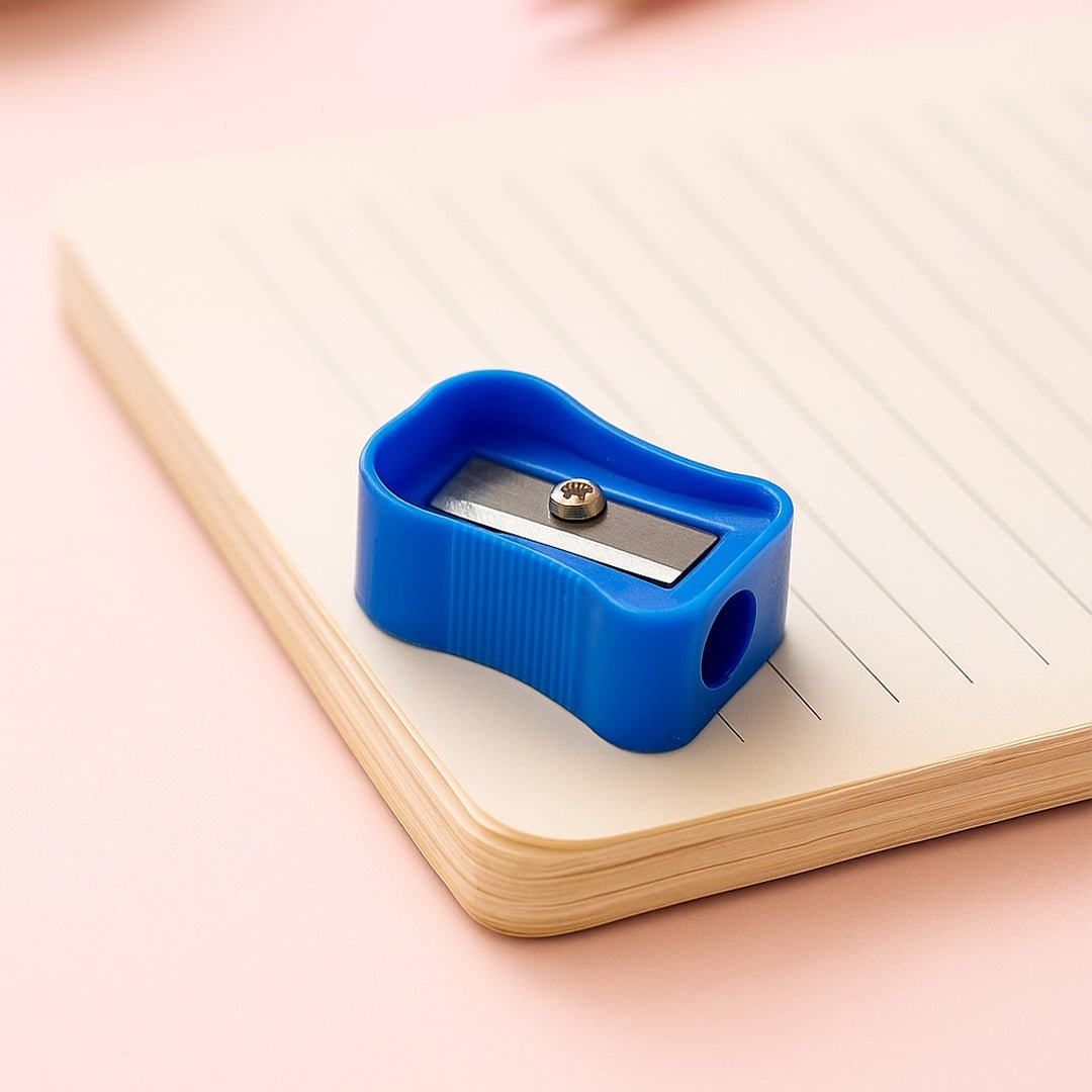 Blue pencil sharpener on a notebook with a pink background