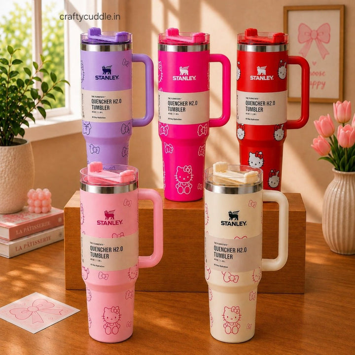 Hello Kitty Stainless Steel TumblerTumblersCrafty CuddleFive Stanley Quencher H2.0 tumblers with Hello Kitty designs in purple, pink, red, and cream, arranged on a wooden shelf and tabletop in a styled room setting.CreamHello Kitty Tumbler