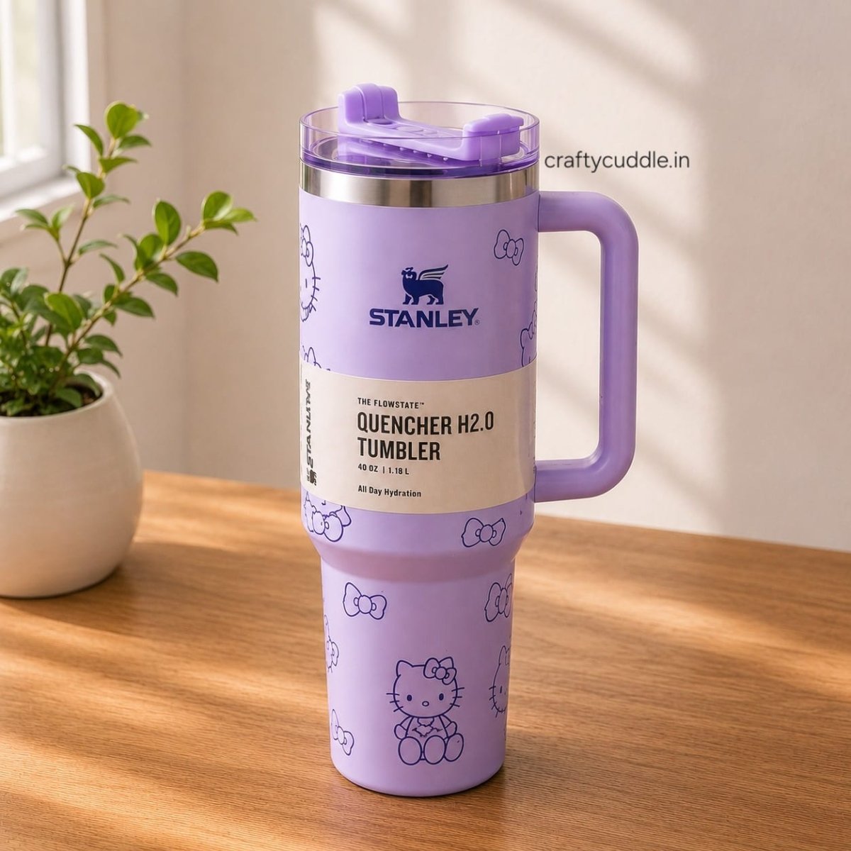 Hello Kitty Stainless Steel TumblerTumblersCrafty CuddleA lavender Stanley Quenchner H2.0 tumbler with a Hello Kitty pattern, featuring a built-in handle and lid, sitting on a wooden table next to a potted plant.CreamHello Kitty Tumbler