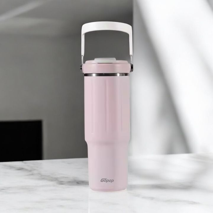 Pink insulated bottle with a white handle on a marble surface