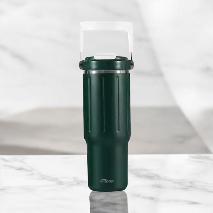 Green travel mug with a white handle on a marble surface