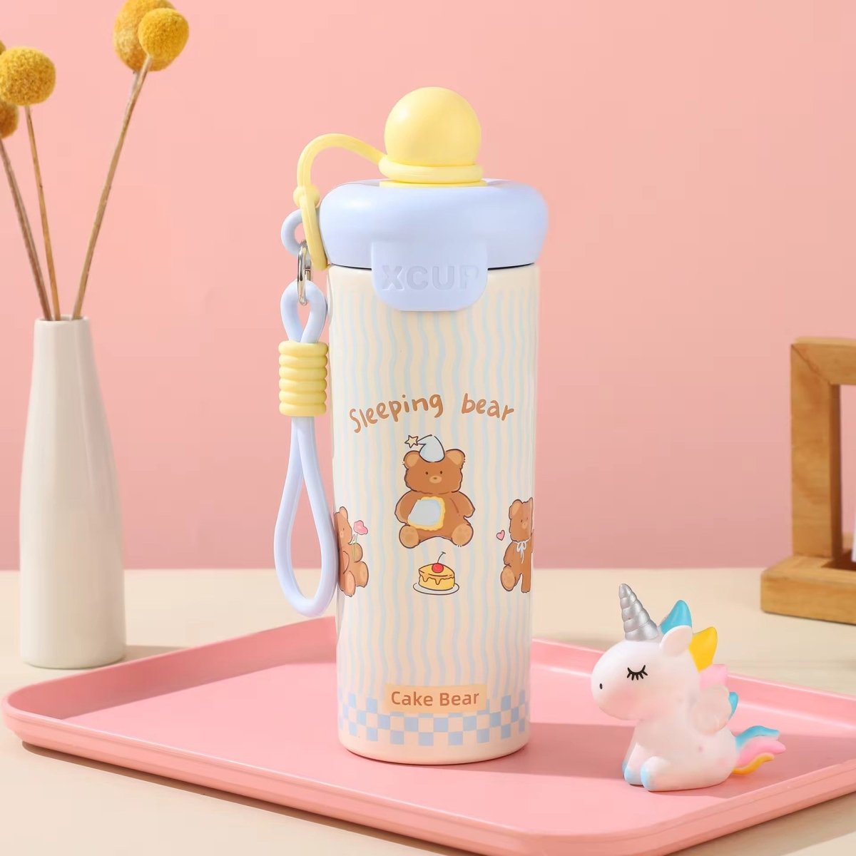 Kids Insulated Water BottleCartoon Kids Water BottleCrafty CuddleA cute water bottle with a cartoon bear design, resting on a pink tray next to a small unicorn figurine. The background is a soft pink wall with a vase of yellow flowers.BlackStainlessSteelBottle InsulatedBottle WaterBottle KidsWaterBottle LeakproofBottle ReusableBottle SchoolEssentials TravelBottle HydrationOnTheGo CuteWaterBottle