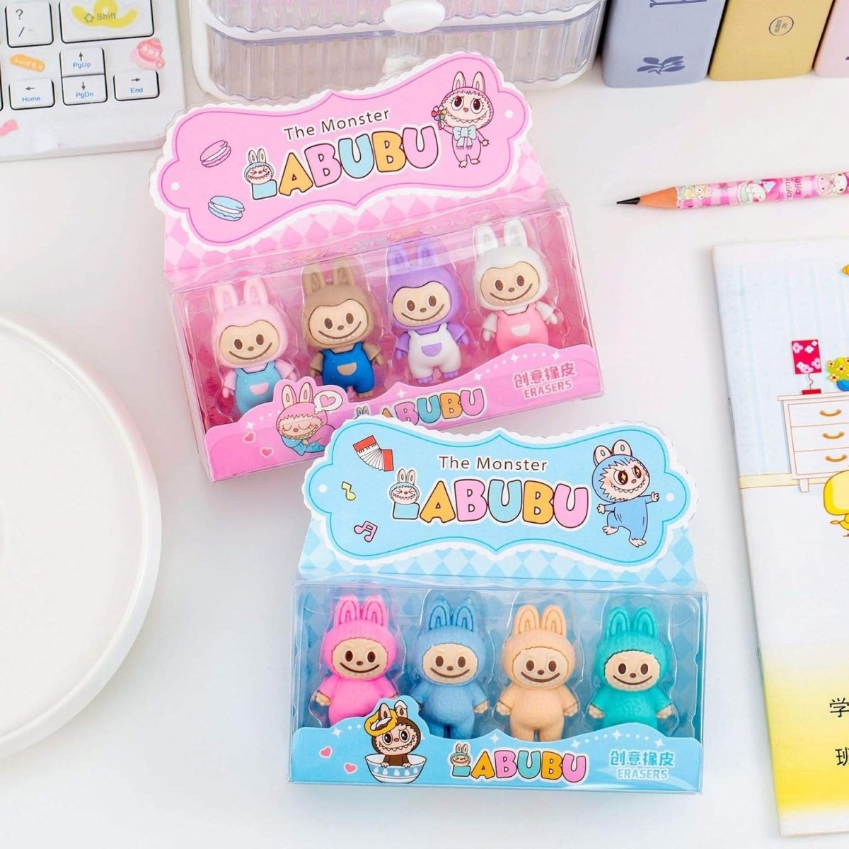 Two packages of Labubu figurines on a white surface with stationery items.