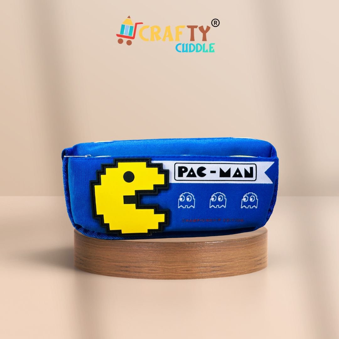 Pac-Man themed blue pencil pouch for kids featuring a red pixelated Pac-Man design and ghost icons, labeled "Championship Edition", displayed on a wooden platform with a peach background. Crafty Cuddle logo on top.