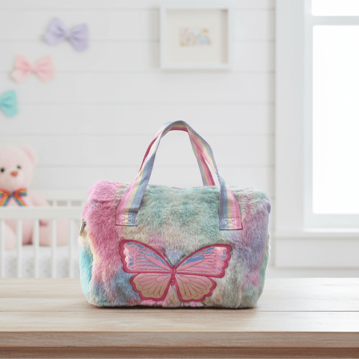 Pastel Butterfly Handbag for GirlsKids BagsCRAFTY CUDDLEMulticolored plush bag with a butterfly design on a surface, with a baby crib and colorful bows in the background.Multicolor