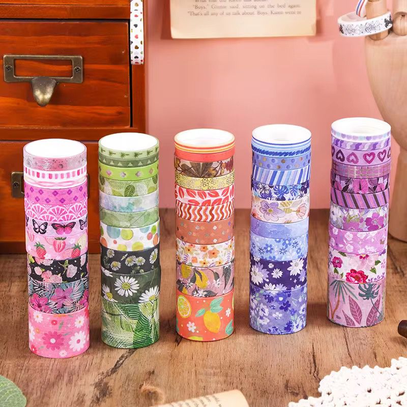 Pastel Floral Washi Tape – 50 RollsDecorative Washi TapeCRAFTY CUDDLESet of colorful washi tape rolls on a wooden surface with a pink wall in the background.washitape washitapelove washitapecollection papercrafts diycrafts journaling bulletjournal plannerdecor creativejournaling stationerylovers aestheticstationery