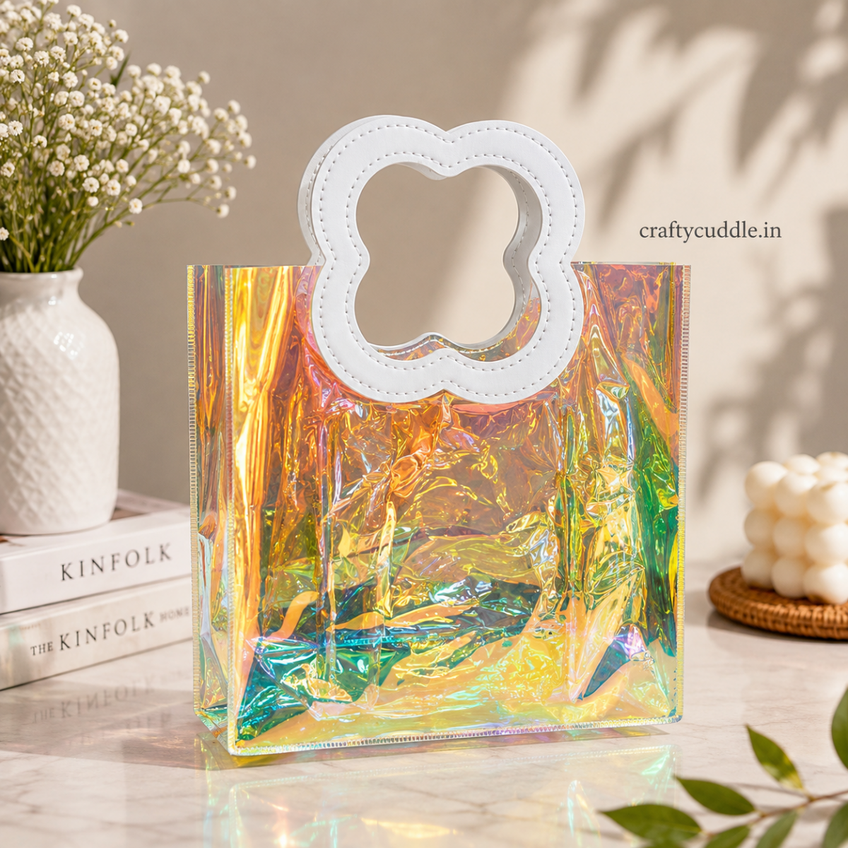 Pretty Shimmer Tote BagTransparent bagCrafty CuddleAn iridescent holographic clear tote bag with a white faux-leather handle, styled on a marble tabletop with baby's breath flowers and books in the background.WhiteGiftHampers GiftPackaging GiftBag IridescentBag GiftIdeas ReturnGifts PartyFavours BirthdayGifts FestiveGifting GiftWrap TrendyBags ReusableBag