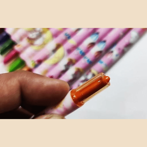 Close-up of a hand holding an orange pen with a colorful pencil background