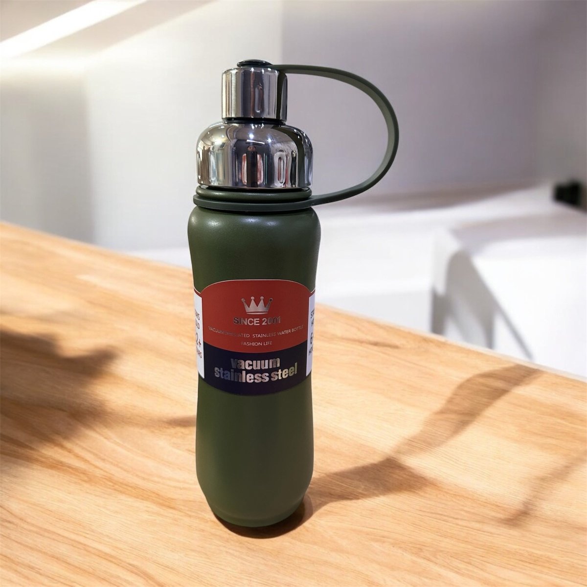 Green water bottle with a label on a wooden surface
