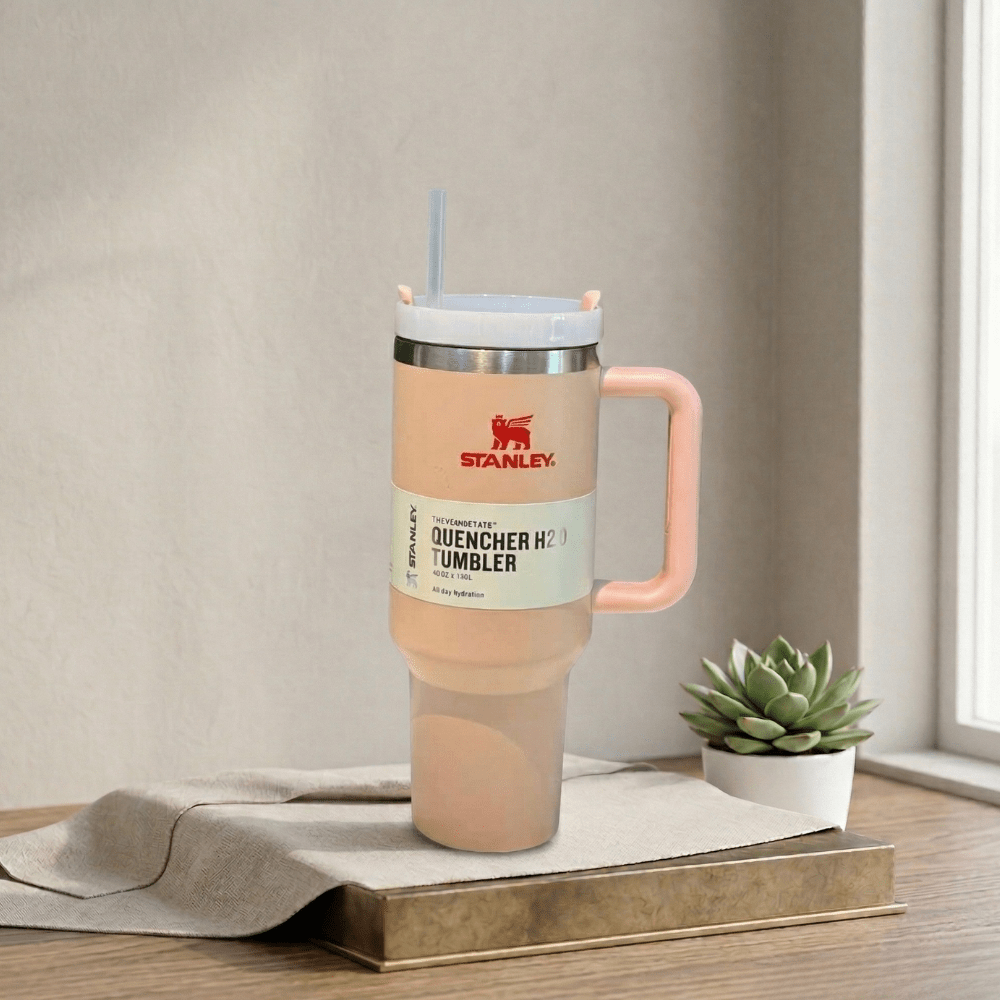 Stanley TumblerDrinkwareCrafty CuddleStanley tumbler with pink handle on a wooden surface with a plant in the backgroundStanley Tumbler-4PeachAestheticVibesAmazonFinds