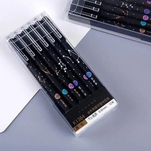 Set of black pens with star constellation designs in a clear packaging on a gray surface.