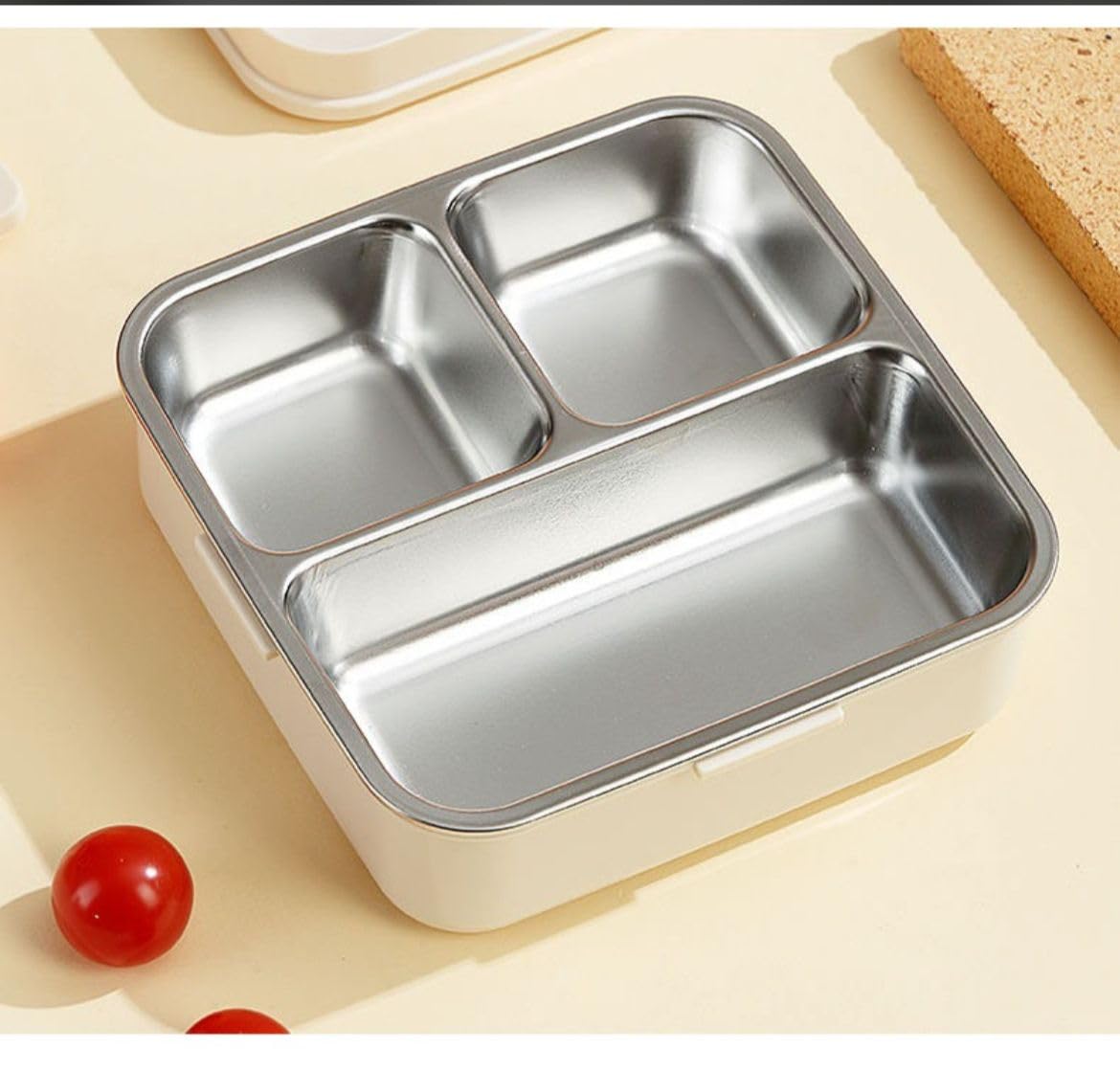 "Open stainless steel lunch box with an elephant-themed design, featuring multiple compartments filled with a colorful meal—rice with vegetables, dragon fruit, cherry tomatoes, and donuts. Includes a spoon and playful accessories, placed on a light-colored surface. Ideal for durable, eco-friendly food storage, meal prep, and school lunches.