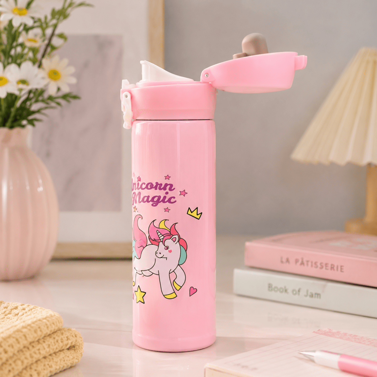 Unicorn Magic Kids Insulated Water BottleCartoon Kids Water BottleCrafty CuddlePink water bottle with unicorn design on a desk with books and flowers.StationeryAddict