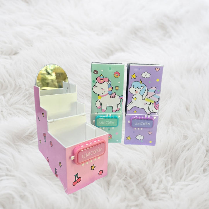 Unicorn Magic pop-up pen stands displayed—one pink box open showing mirror and compartments, and two others closed in lavender and Light green colors.
