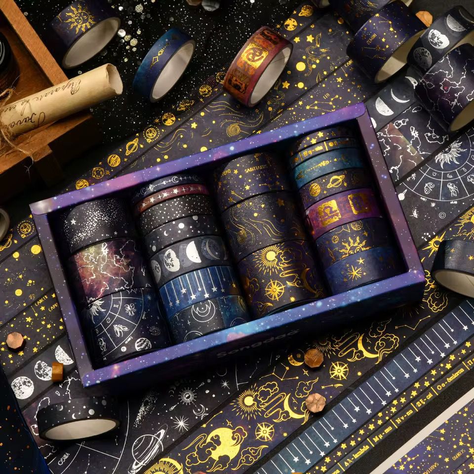 Washi Tape – 20 pcs Vast Universe SeriesCRAFTY CUDDLESet of washi tape rolls with celestial designs in a decorative box on a matching background.