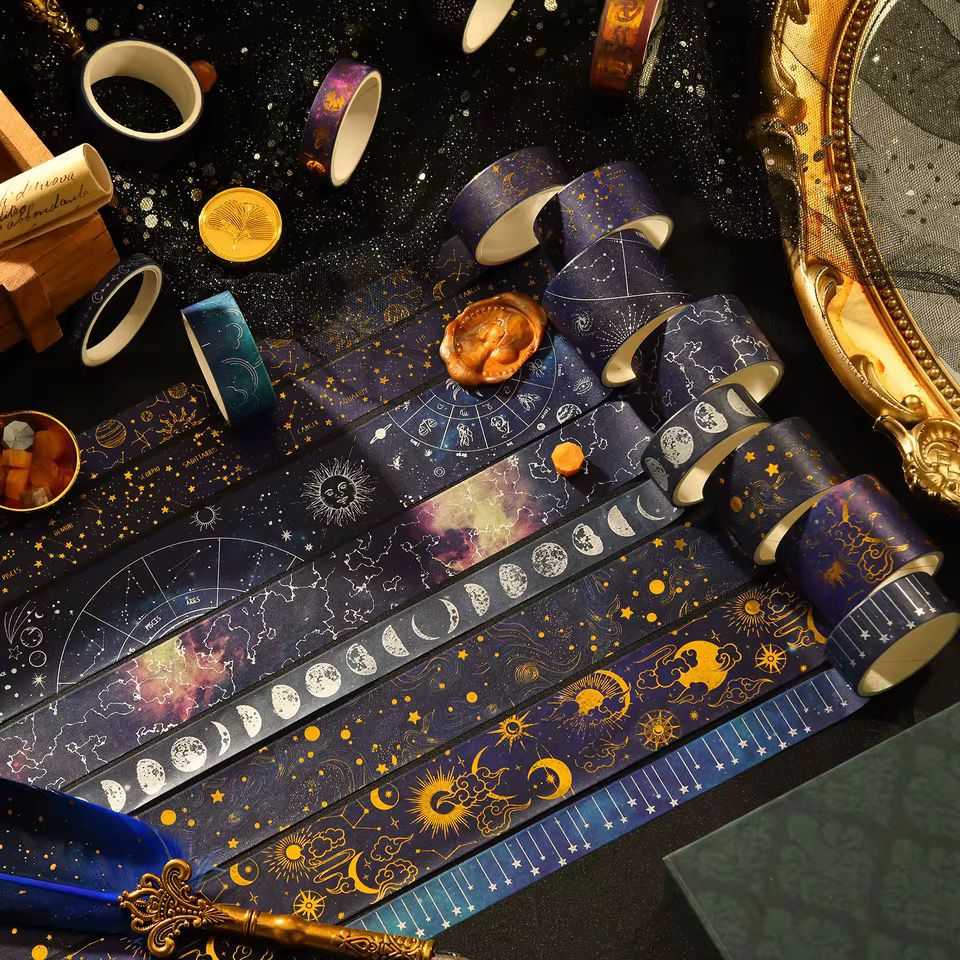 Washi Tape – 20 pcs Vast Universe SeriesCRAFTY CUDDLERolls of tape with celestial designs on a dark surface